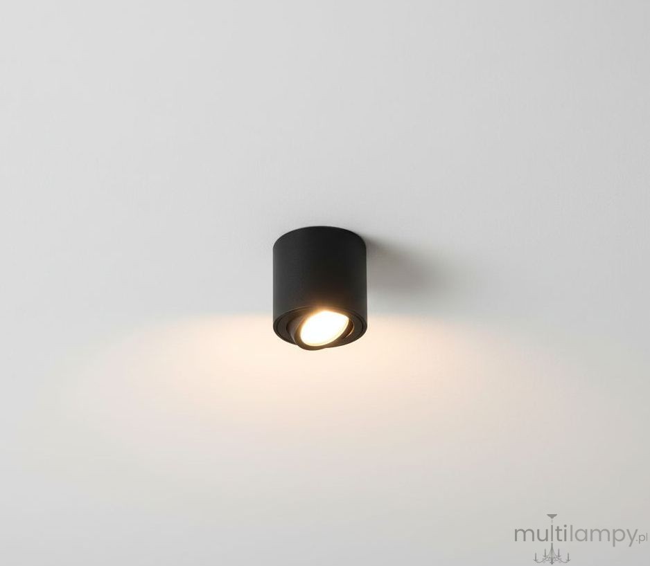 Mini lampa sufitowa tuba w kolorze czarnym, zamontowana na białym suficie. Okrągły kształt z widocznym źródłem światła, skierowany w dół, emitujący ciepłe światło. Prosty design, idealna do oświetlenia wnętrz.