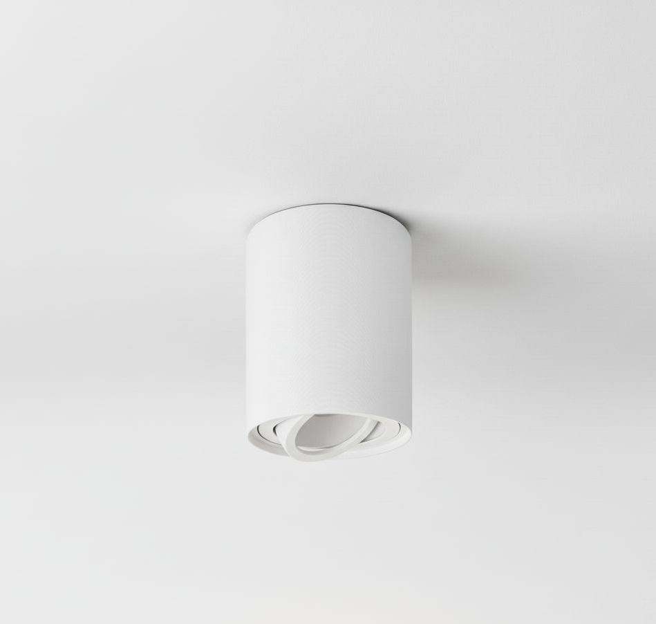 Biała lampa sufitowa w formie tuby, zamontowana na suficie. Okrągły kształt z widocznym mechanizmem kierunkowym wewnątrz. Prosty design, pasujący do nowoczesnych wnętrz. Tło zdjęcia jasne, co podkreśla kolor lampy.