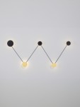 Kinkiet Cliza 5xLED 34W w kolorze czarnym i złotym, składający się z pięciu okrągłych elementów o różnej średnicy, połączonych czarnymi przewodami, zamontowany na jasnej ścianie.