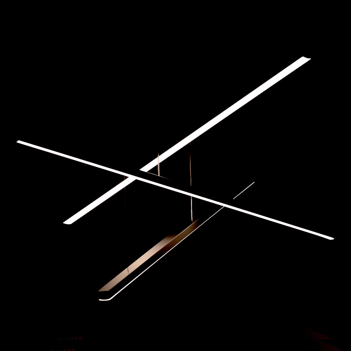 Trio LED lampa wisząca 3-punktowa czarna, z trzema równoległymi, prostokątnymi paskami świetlnymi w kolorze białym, zawieszona na cienkich linkach, prezentująca nowoczesny, minimalistyczny design. Ujęcie z góry, na czarnym tle.