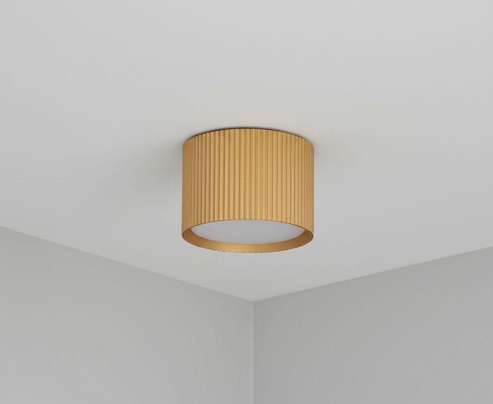 Lampa sufitowa Gisele w kształcie tuby, wykonana z metalowego materiału w odcieniu złotym, z teksturowaną powierzchnią. Zainstalowana na suficie, z okrągłym źródłem światła. Prosta, nowoczesna forma, odpowiednia do różnych aranżacji wnętrz.