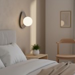 Kinkiet Ovo 1xG9 w kolorze szarym, z okrągłą, białą oprawą świetlną, zamontowany na ścianie obok łóżka. W tle widoczny stolik nocny z rośliną oraz drewniane krzesło. Prosta aranżacja wnętrza z neutralnym tłem.