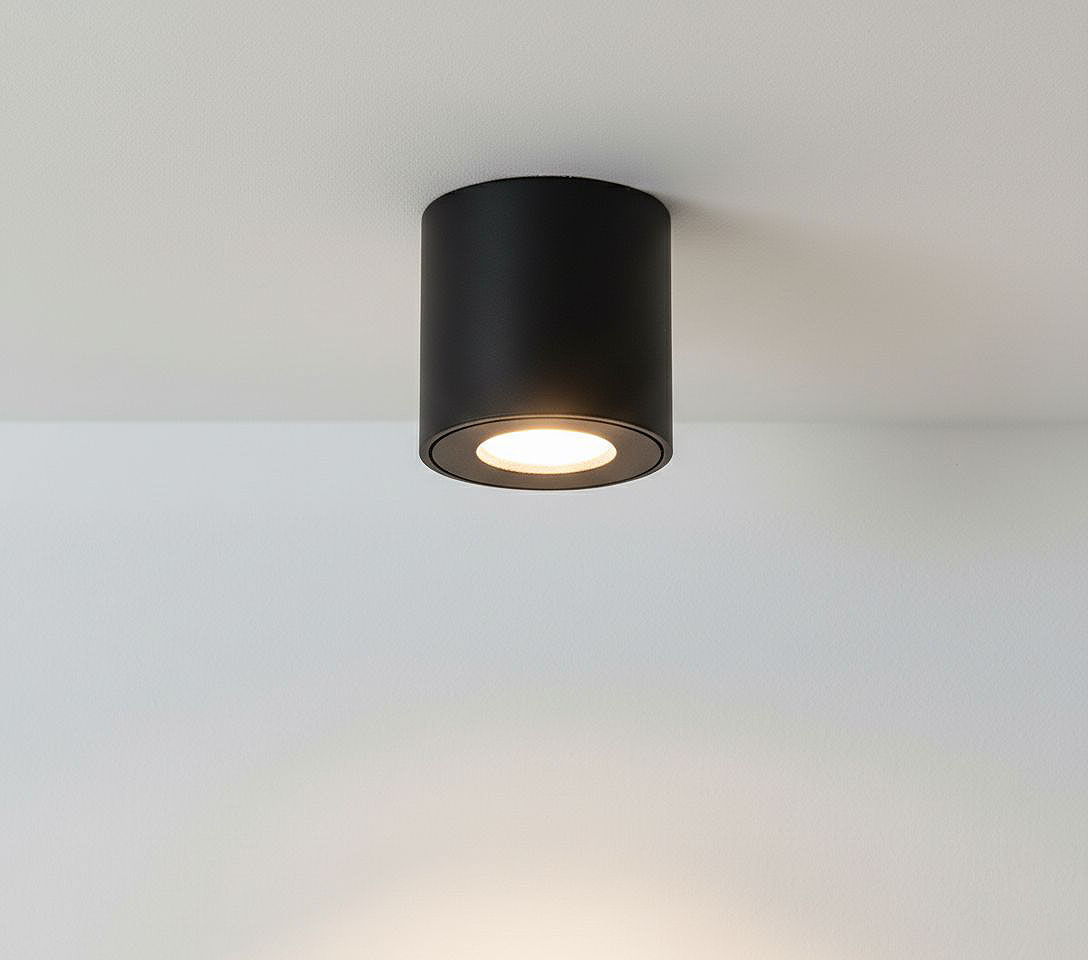 Czarna lampa sufitowa tuba Aqua IP54, zamontowana na suficie, z okrągłym źródłem światła widocznym w środku. Prosta, cylindryczna forma, idealna do łazienki, na jasnym tle.