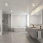 Lampa sufitowa Aqua 2 IP54 w białej obudowie, zamontowana na suficie łazienki. Okrągły kształt, minimalistyczny design. Widoczna w nowoczesnym wnętrzu z wanną, umywalką i szklanym prysznicem na tle jasnych płytek.