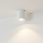 Lampa sufitowa Aqua 2 w kolorze białym, o cylindrycznym kształcie, zamontowana na suficie. Posiada okrągłe źródło światła, idealna do łazienek, z certyfikatem IP54, co gwarantuje odporność na wilgoć. Tło proste, białe.