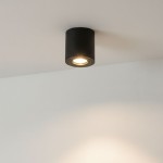 Czarna lampa sufitowa tuba Aqua 2 IP54, zamontowana na suficie, z okrągłym otworem emitującym światło. Minimalistyczny design, idealna do łazienki. Wykonana z materiałów odpornych na wilgoć.