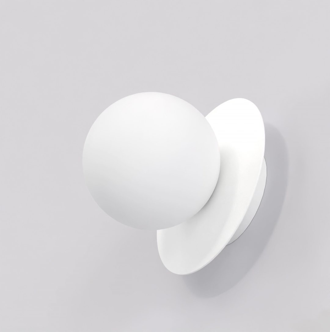 Biały kinkiet Americana 1xG9 z okrągłą, matową głowicą i płaską, okrągłą podstawą. Produkt zamontowany na gładkiej, jasnej ścianie, widok z przodu, podkreślający minimalistyczny design i nowoczesną formę.