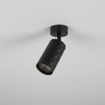 Czarna lampa sufitowa spot GU10 o geometrycznym, sześciokątnym kształcie. Ujęcie z dołu, produkt zamontowany na suficie. Materiał z matową teksturą, widoczna oprawa żarówki. Proste tło w jasnym kolorze.