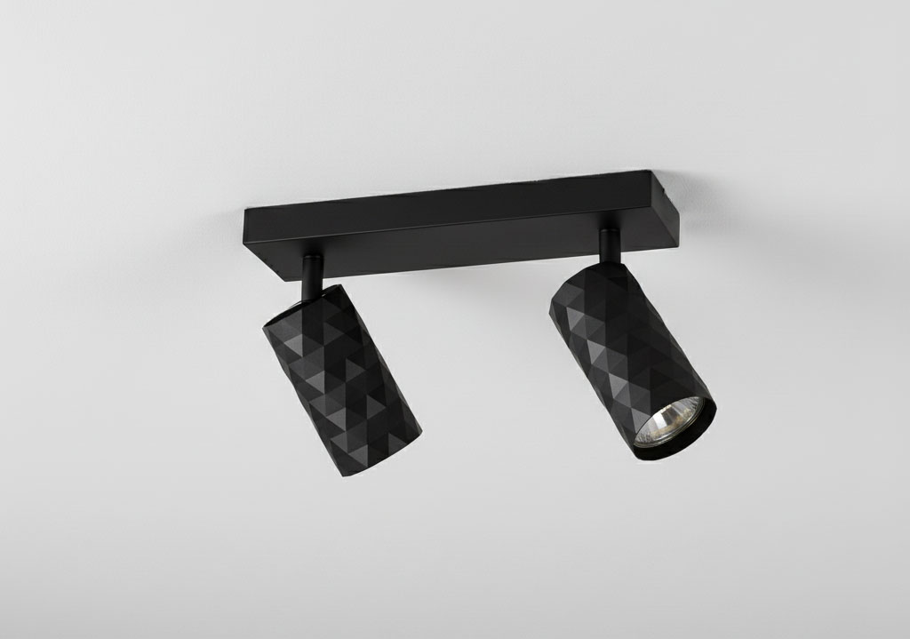 Czarna lampa sufitowa typu spot z dwoma reflektorami GU10. Reflektory posiadają teksturowaną, wieloboczną powierzchnię. Lampa zamontowana poziomo na prostokątnej podstawie. Idealna do nowoczesnych wnętrz.