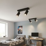 Czarna lampa sufitowa typu spot z dwoma oprawami GU10, zamontowana na suficie. Widoczne reflektory skierowane w różne strony, umieszczone w nowoczesnym wnętrzu z biurkiem, łóżkiem i dekoracjami na ścianie.