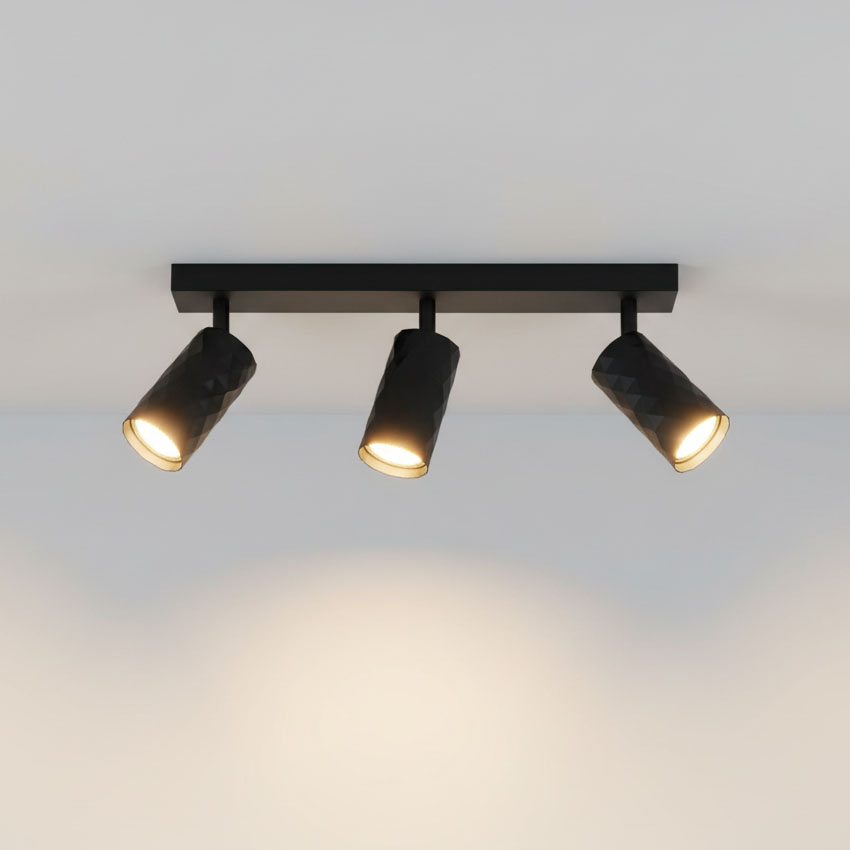 Czarna lampa sufitowa typu spot z trzema głowicami GU10, umieszczona na prostokątnej podstawie. Głowice mają fakturę w formie diamentowego wzoru, skierowane w różne strony, emitując ciepłe światło na gładkim tle.