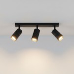 Czarna lampa sufitowa typu spot z trzema głowicami GU10, umieszczona na prostokątnej podstawie. Głowice mają fakturę w formie diamentowego wzoru, skierowane w różne strony, emitując ciepłe światło na gładkim tle.