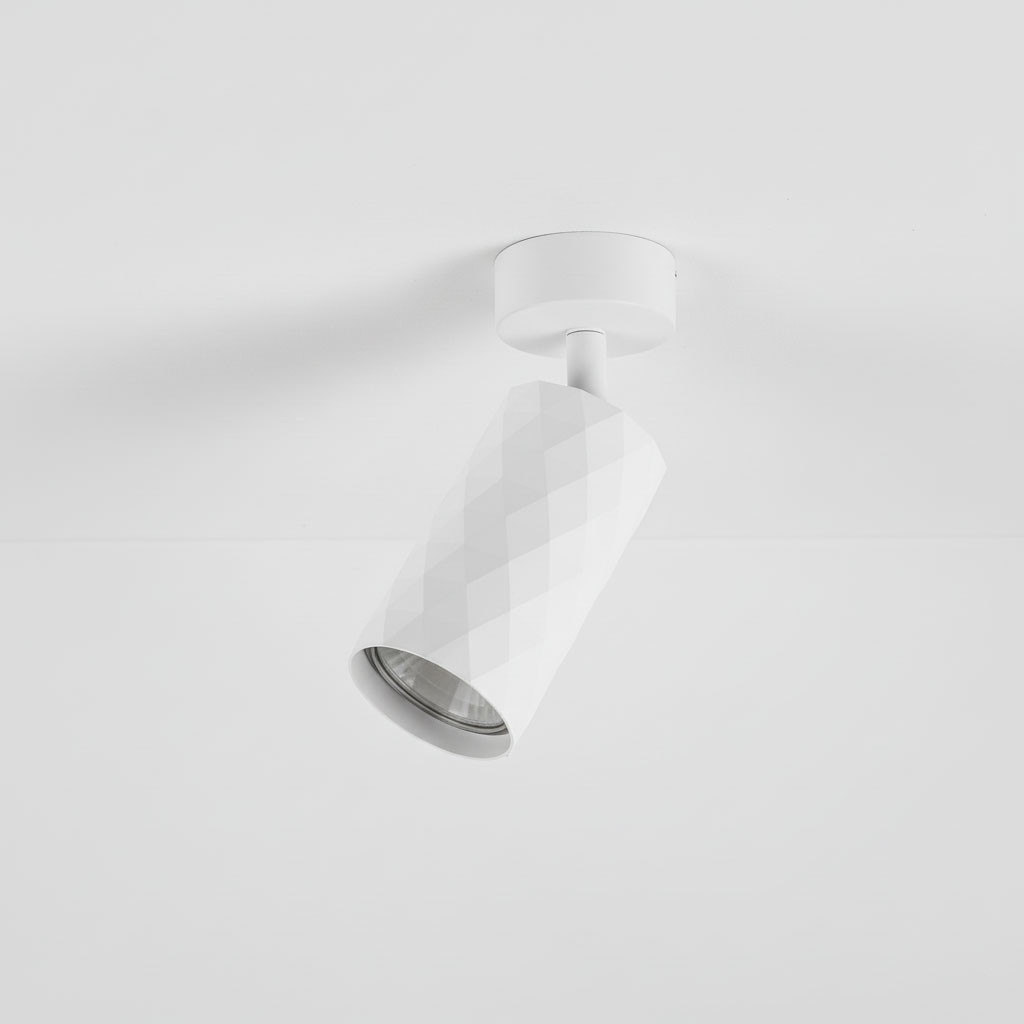 Biała lampa sufitowa typu spot GU10 z geometrycznym, żłobkowanym kloszem. Ujęcie z boku, montowana na suficie. Prosta forma idealna do nowoczesnych wnętrz, emitująca skierowane światło.
