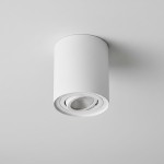 Lampa sufitowa Devo w białej obudowie, w kształcie tuby, z jednym gniazdem GU10. Zainstalowana na suficie, z widoczną soczewką wewnętrzną. Prosty, nowoczesny design, idealna do oświetlenia kierunkowego.