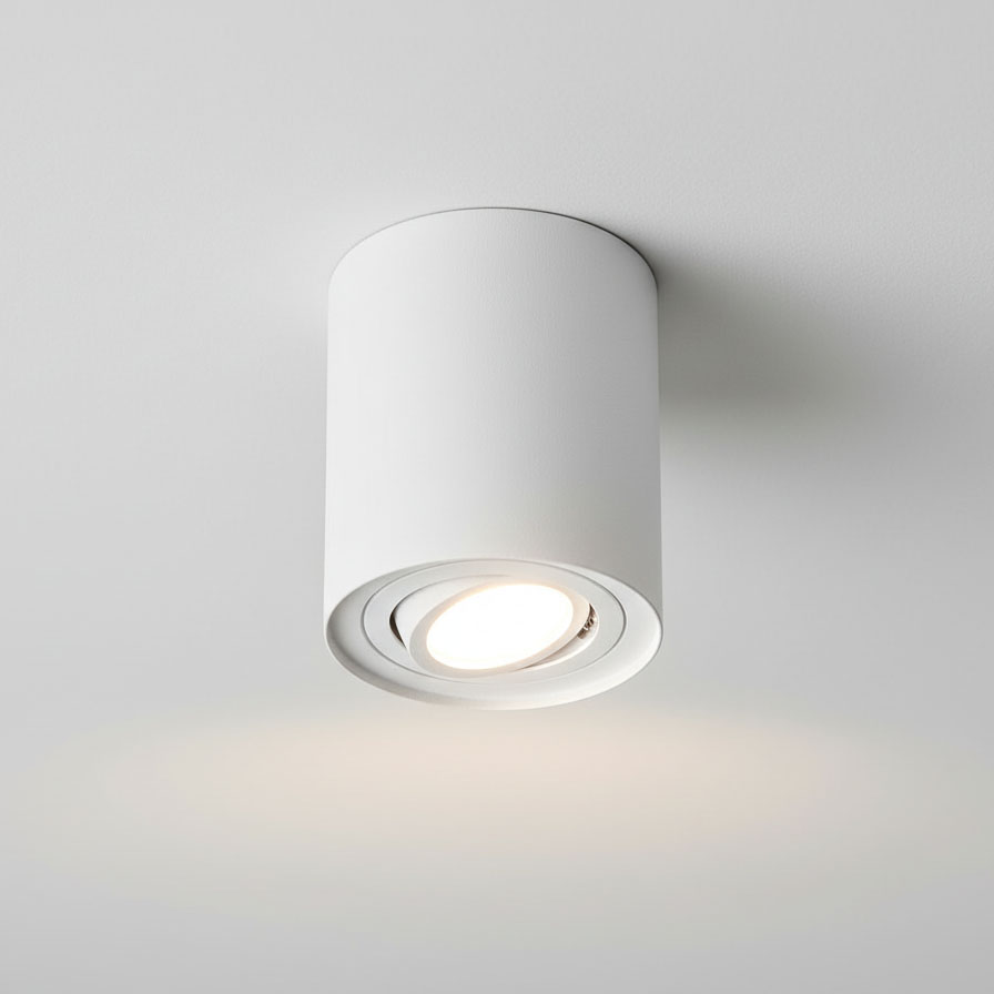 Biała lampa sufitowa w formie tuby, z zamontowanym źródłem światła GU10. Ujęcie z dołu, pokazujące okrągły kształt i wykończenie. Lampa kierunkowa, montowana na suficie, o minimalistycznym designie.