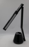 Czarna lampka biurkowa Kiki z LED 8W, z regulowanym ramieniem. Kształt stożkowaty u podstawy z panelem sterującym. Wysoka, smukła konstrukcja z matowym wykończeniem, stojąca na białym tle.