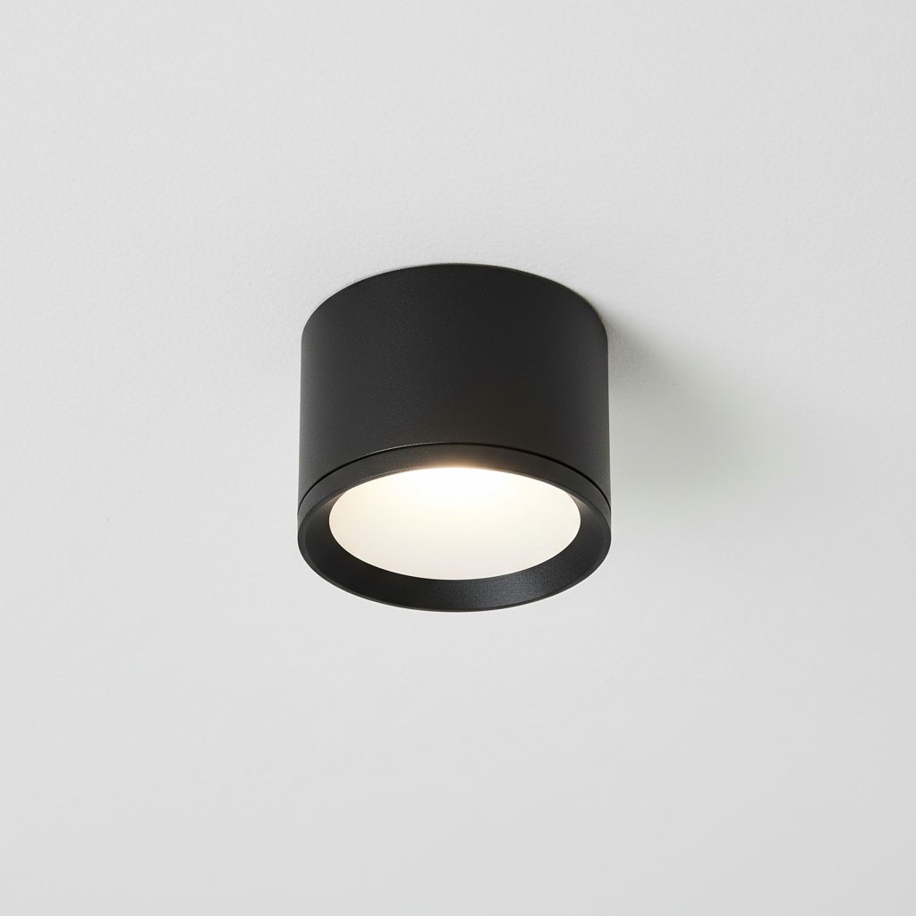 Czarna lampa sufitowa tuba GX53/IP54, okrągła, zamontowana na białym suficie. Posiada matową powierzchnię i emituje miękkie, białe światło. Idealna do użytku wewnętrznego i zewnętrznego.