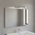 Kinkiet łazienkowy LED Lappa w kolorze chromowanym, zamontowany nad lustrem. Prosty, prostokątny kształt, emitujący jasne światło, na tle jasnych płytek ceramicznych. Idealny do oświetlenia przestrzeni łazienkowej.