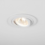 Oprawa podtynkowa ruchoma GU10 w kolorze białym, zamontowana w suficie. Widać lekko wypukłą obudowę z metalicznym wykończeniem oraz źródło światła w centralnej części, emitujące jasne światło.