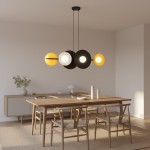 Lampa wisząca Volum 6xG9 w kolorze czarnym z żółtymi i białymi elementami, zawieszona na dwóch cienkich linkach. Produkt umieszczony nad drewnianym stołem w minimalistycznym wnętrzu, w tle widoczna szafka i roślinność.