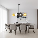 Lampa wisząca Volum w kolorze czarnym z mixem sześciu okrągłych kloszy w odcieniach białym, żółtym i czarnym, zawieszona nad drewnianym stołem w nowoczesnej jadalni, otoczona szarymi krzesłami.