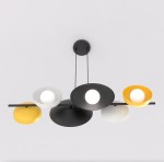 Lampa wisząca Volum w kolorze czarnym, z sześcioma kloszami w różnych kolorach (czarnym, białym i żółtym). Klosze mają okrągły kształt z centralnym źródłem światła. Ujęcie z góry, wisząca na dwóch kabelkach.
