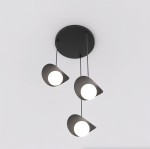 Lampa wisząca Ritual z trzema kloszami G9 w kolorze czarnym, zawieszona na cienkich linkach. Klosze mają asymetryczny kształt i emitują białe światło. Montaż sufitowy, minimalistyczny design na jasnym tle.