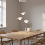 Lampa wisząca Ritual 3xG9 w kolorze białym, z trzema okrągłymi kloszami zawieszonymi na cienkich linkach. Elementy o minimalistycznym designie, zawieszone nad drewnianym stołem w jasnym wnętrzu. W tle okno i dekoracje.