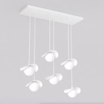 Lampa wisząca Ritual w kolorze białym, z sześcioma źródłami światła G9. Okrągłe klosze z płaskimi osłonami, zawieszone na cienkich linkach z prostokątną podstawą. Ujęcie frontalne, na szarym tle.