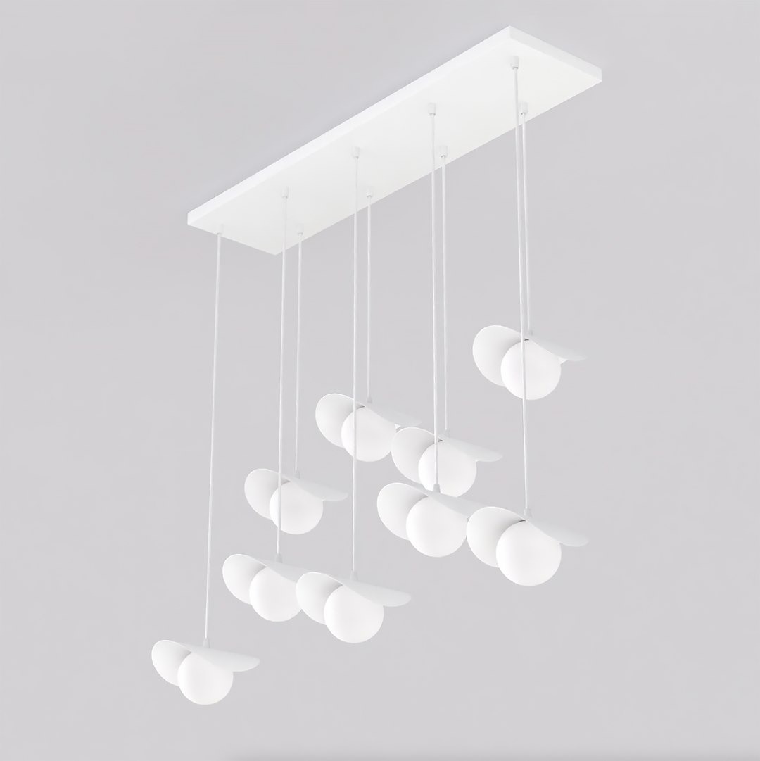 Lampa wisząca Ritual 9xG9 w kolorze białym z prostokątnym stelażem. Posiada dziewięć okrągłych kloszy zawieszonych na cienkich linkach. Klosze mają delikatne, zaokrąglone kształty, co nadaje lampie nowoczesny wygląd.