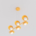 Pomarańczowa lampa wisząca Boom z sześcioma oprawami G9, zawieszona na cienkich linkach. Kształt cylindryczny z białymi kloszami w formie misek. Wisi pod sufitem na okrągłej podstawie, na jednolitym tle.
