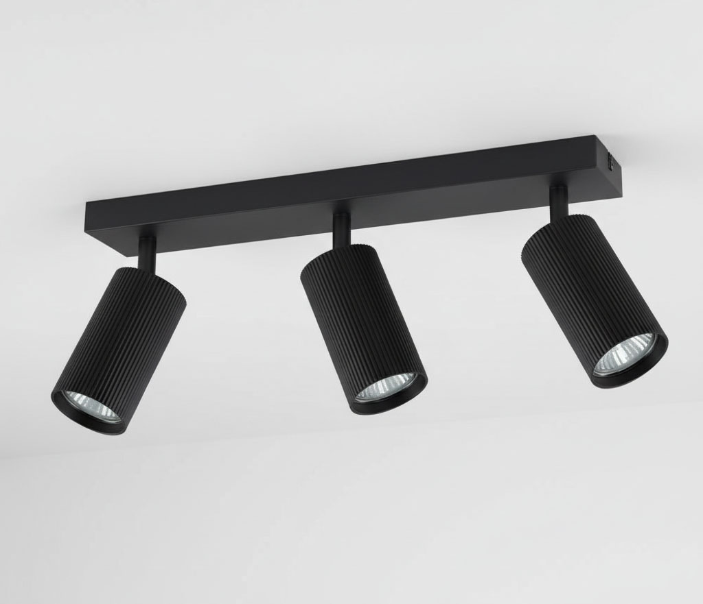 Lampa sufitowa Lucerno w kolorze czarnym z trzema reflektorami GU10. Reflektory o cylindrycznym kształcie z rowkowaną powierzchnią zamontowane na prostokątnej, czarnej podstawie. Ujęcie z dołu, ukazujące całość konstrukcji.