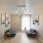 Lampa sufitowa Lucerno w kolorze białym z dwoma ruchomymi punktami świetlnymi, zamontowana na suficie. W tle widoczne szare sofy, okno z firaną i dekoracyjne obrazy na ścianach. W otoczeniu stół z rośliną doniczkową.