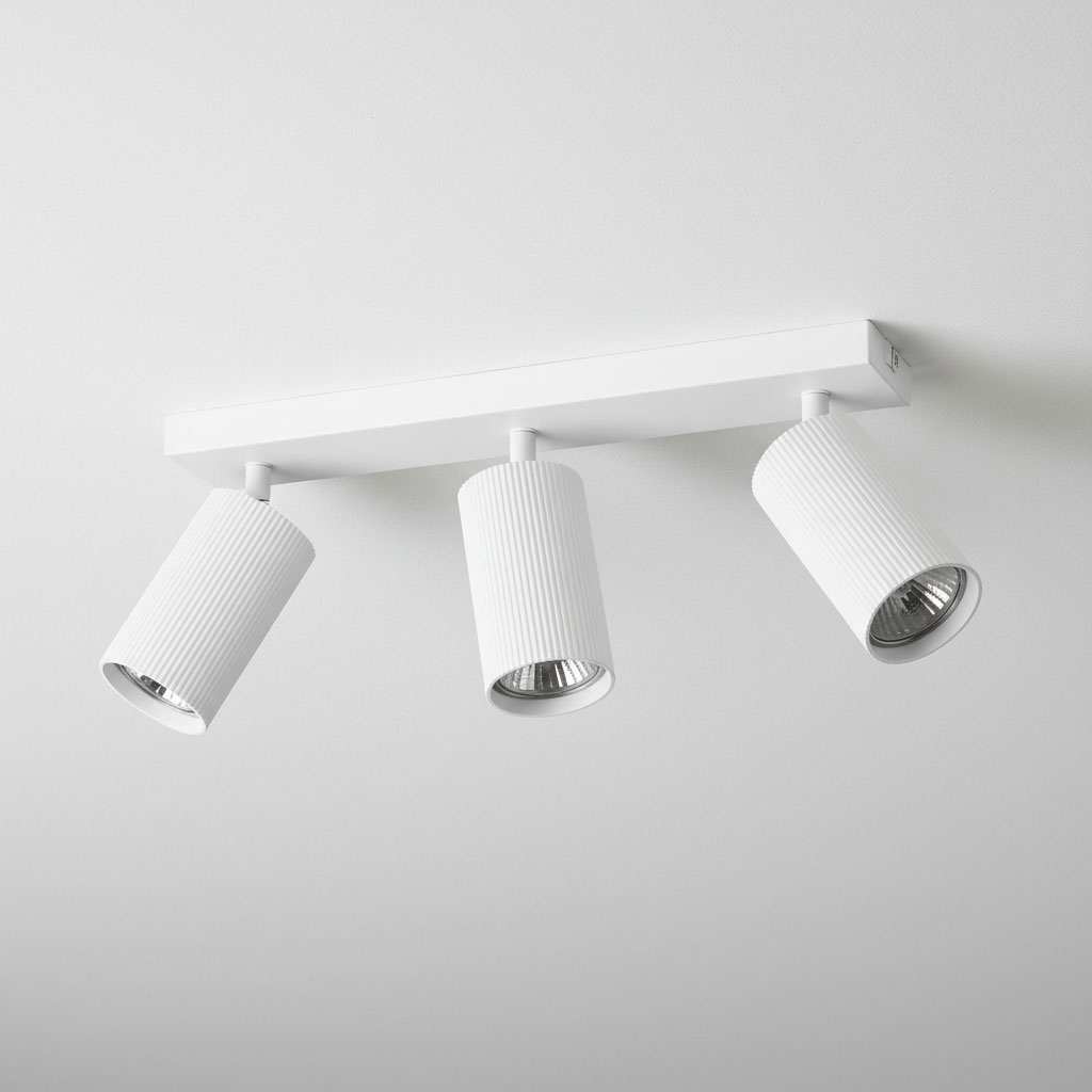 Lampa sufitowa Lucerno w kolorze białym z trzema regulowanymi kloszami w kształcie cylindrów, umieszczona na prostokątnej, płaskiej podstawie. Klosze mają żebrowaną fakturę, co dodaje ciekawego akcentu wizualnego.