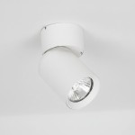 Biała lampa sufitowa typu spot, montowana na suficie, w kształcie cylindrycznym. Kąt ujęcia z boku, ukazujący detal reflektora. Prosta konstrukcja, idealna do nowoczesnych wnętrz.