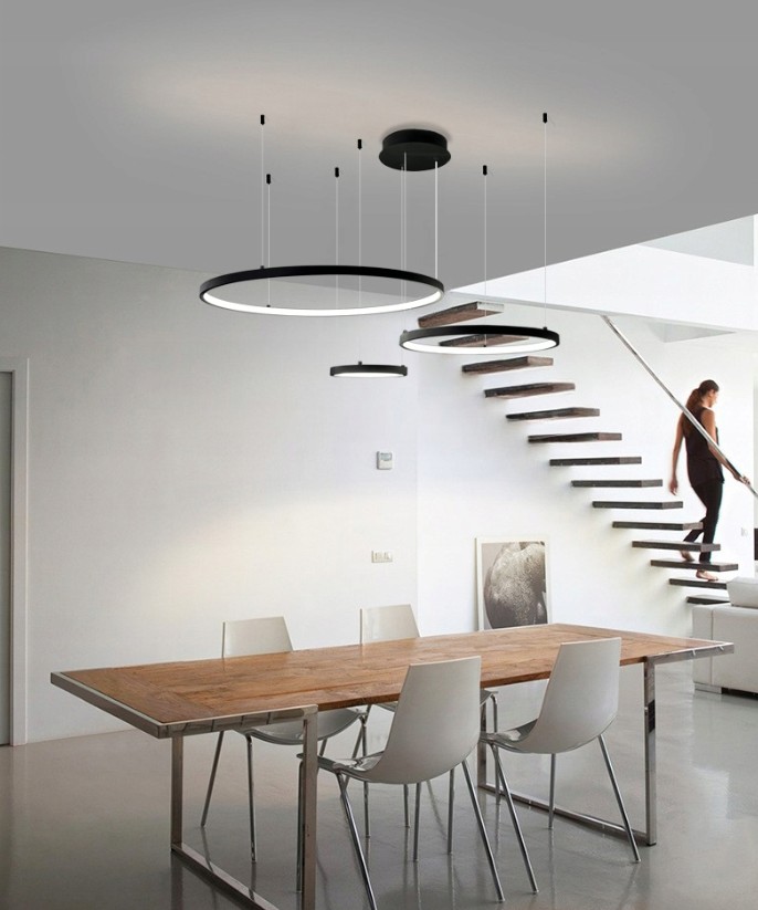 Lampa wisząca LED Hodo w kolorze czarnym, z pilotem, dostępna w trzech długościach (20/40/60 cm). Zawieszona na cienkich linkach, umieszczona nad drewnianym stołem w nowoczesnym wnętrzu. Widoczne dwa okrągłe klosze w różnej średnicy.