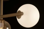 Beżowa lampa sufitowa Lemo z trzema oprawami G9, z bliskim ujęciem okrągłego klosza z matowego szkła, zamocowanego na metalowym ramieniu. Klosz jest osadzony na prostym, eleganckim stelażu w neutralnym kolorze. Tło ciemne.