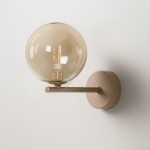 Beżowy kinkiet Lemo z pojedynczym źródłem światła G9. Okrągła, przezroczysta klosz w kolorze brązowym, zamocowany na prostym, metalowym ramieniu. Produkt montowany na ścianie, w minimalistycznym stylu.