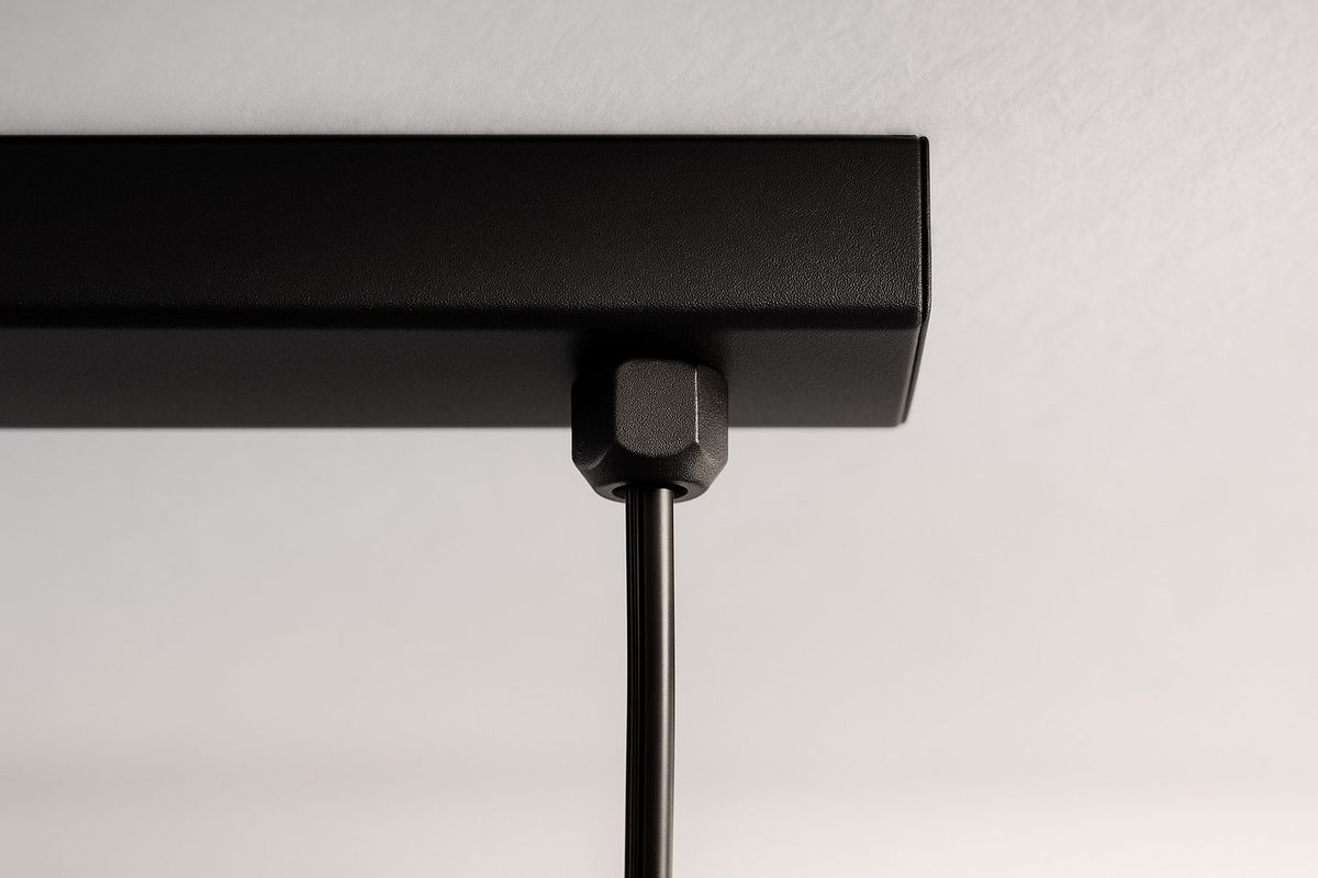 Czarna lampa wisząca Filo z pięcioma miejscami na żarówki G9, widoczna z bliska, z metalowym stelażem o matowej fakturze. Kabel zasilający wisi prosto z sufitu, a uchwyt montażowy jest wyraźnie widoczny. Tło białe, co podkreśla elegancję lampy.