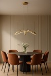 Lampa wisząca Snow 1xLED 40W CCT w kolorze złotym, o nowoczesnym kształcie, zawieszona nad okrągłym stołem. Obok znajdują się brązowe krzesła oraz wazon z białymi kwiatami. Tło w jasnym odcieniu, minimalistyczne.