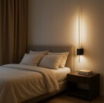 Kinkiet LED Como 90, o mocy 9W i barwie 4000K, w kolorze złotym z czarnym elementem. Montowany na ścianie obok łóżka, emituje ciepłe światło, podkreślając nowoczesny design. W tle widoczne łóżko z poduszkami i stolik nocny.