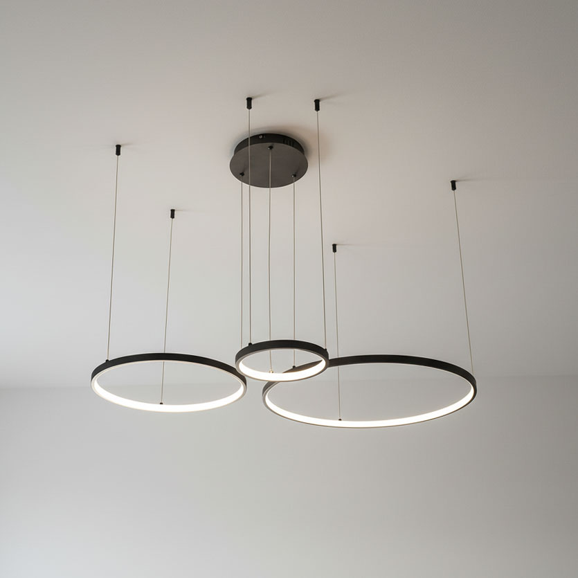 Lampa wisząca LED Hodo w kolorze czarnym, z trzema okrągłymi ramionami o średnicach 20/40/60 cm. Zawieszona na cienkich linkach, z możliwością regulacji wysokości. Wyposażona w pilot do zdalnego sterowania.