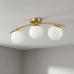 Lampa sufitowa Bali II z trzema kulistymi kloszami w białym kolorze, zamontowana na złotej, łukowatej oprawie. Ujęcie z dołu, pokazujące całość lampy na gładkim, jasnym tle.