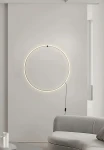 Kinkiet Scopello w kolorze czarnym, z okrągłym, minimalistycznym designem. Zawiera źródło LED 18W CCT, montowany na ścianie. Kable widoczne, lampa emituje ciepłe światło, umiejscowiona na jasnej ścianie obok nowoczesnego mebla.