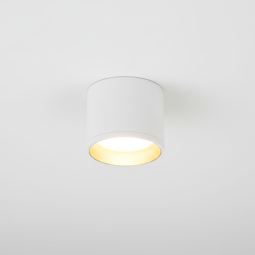 Lampa sufitowa Golda w formie białej tuby z złotym wnętrzem, zamontowana na białym suficie. Wnętrze lampy emituje światło, tworząc kontrast między białą a złotą powierzchnią. Prosty, cylindryczny kształt, do zastosowania w nowoczesnych wnętrzach.