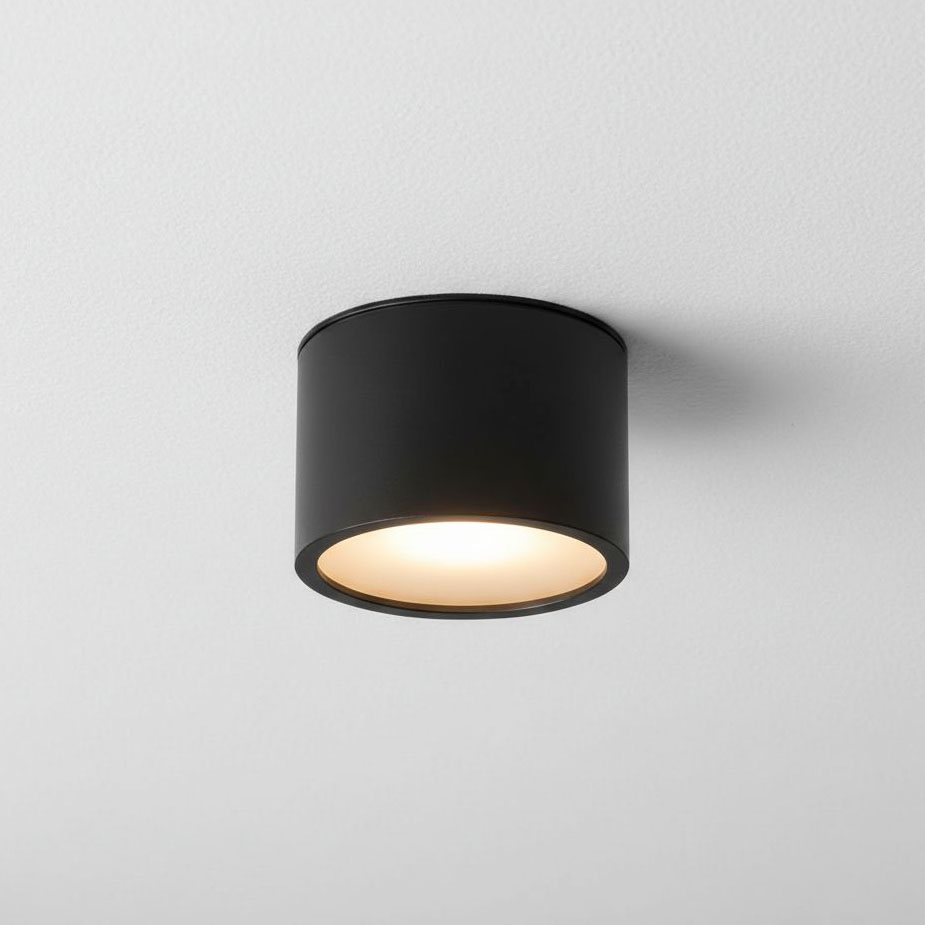 Lampa sufitowa Grandi w kształcie tuby, kolor czarny, o średnicy cylindrycznej. Zainstalowana na suficie, z widoczną żarówką GX53. Ochrona IP54, co zapewnia odporność na kurz i wilgoć. Prosty, nowoczesny design.