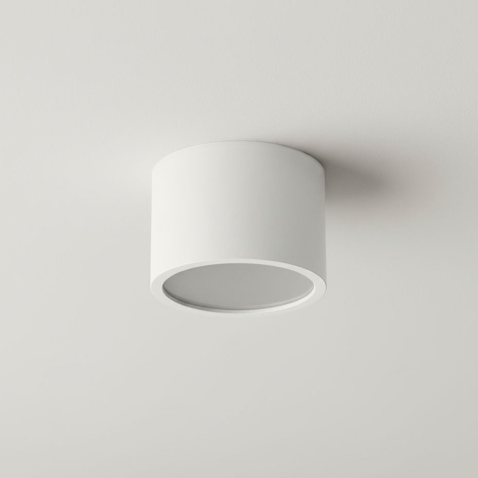 Lampa sufitowa Grandi w kształcie białej tuby, montowana na suficie. Posiada miejsce na żarówkę typu GX53 i jest klasyfikowana jako IP54, co zapewnia odporność na wilgoć. Ujęcie z góry, ukazujące prostą, okrągłą formę.