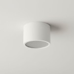 Lampa sufitowa Grandi w kształcie białej tuby, montowana na suficie. Posiada miejsce na żarówkę typu GX53 i jest klasyfikowana jako IP54, co zapewnia odporność na wilgoć. Ujęcie z góry, ukazujące prostą, okrągłą formę.