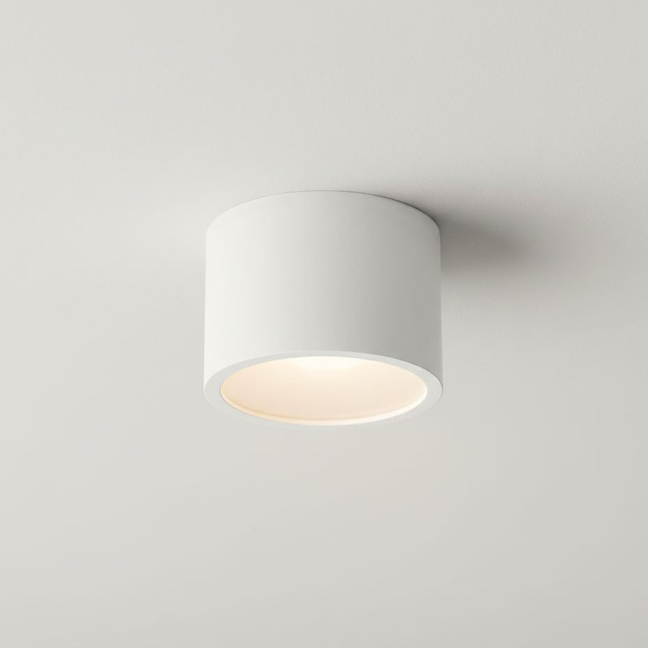 Lampa sufitowa Grandi w kształcie tuby, kolor biała, z jednym gwintem GX53, klasyfikacja IP54. Zainstalowana na suficie, z widocznych detali ma okrągły klosz, emitujący światło w dół. Prosta, minimalistyczna forma.