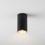Czarna lampa sufitowa w kształcie tuby z wykończeniem w kolorze złotym. Widoczna z przodu, montowana na suficie, z widocznym źródłem światła GU10. Gładka powierzchnia i cylindryczny kształt podkreślają nowoczesny design.